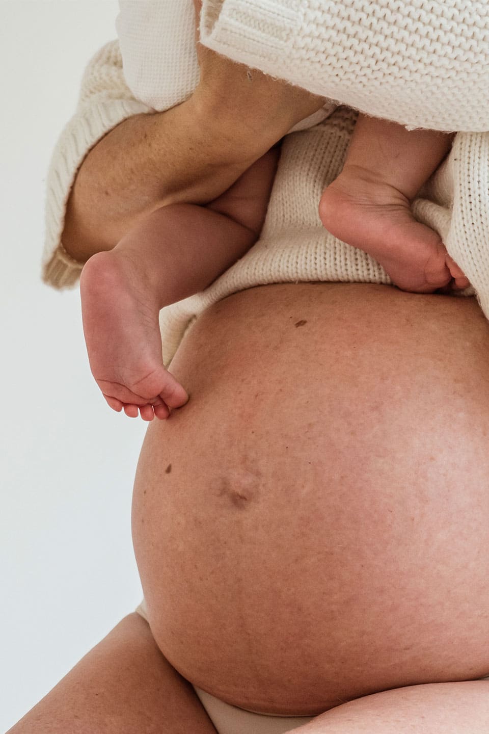 Barriga de mujer embarazada con bebé en brazos